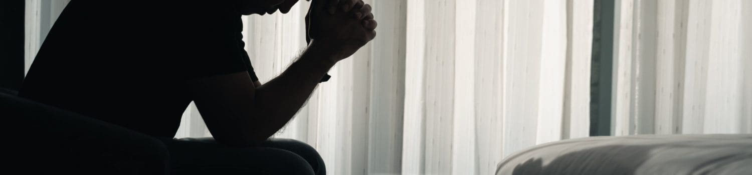 Depressed man sat lonely in a dark room with hands to head Depressed man sat lonely in a dark room with hands to head