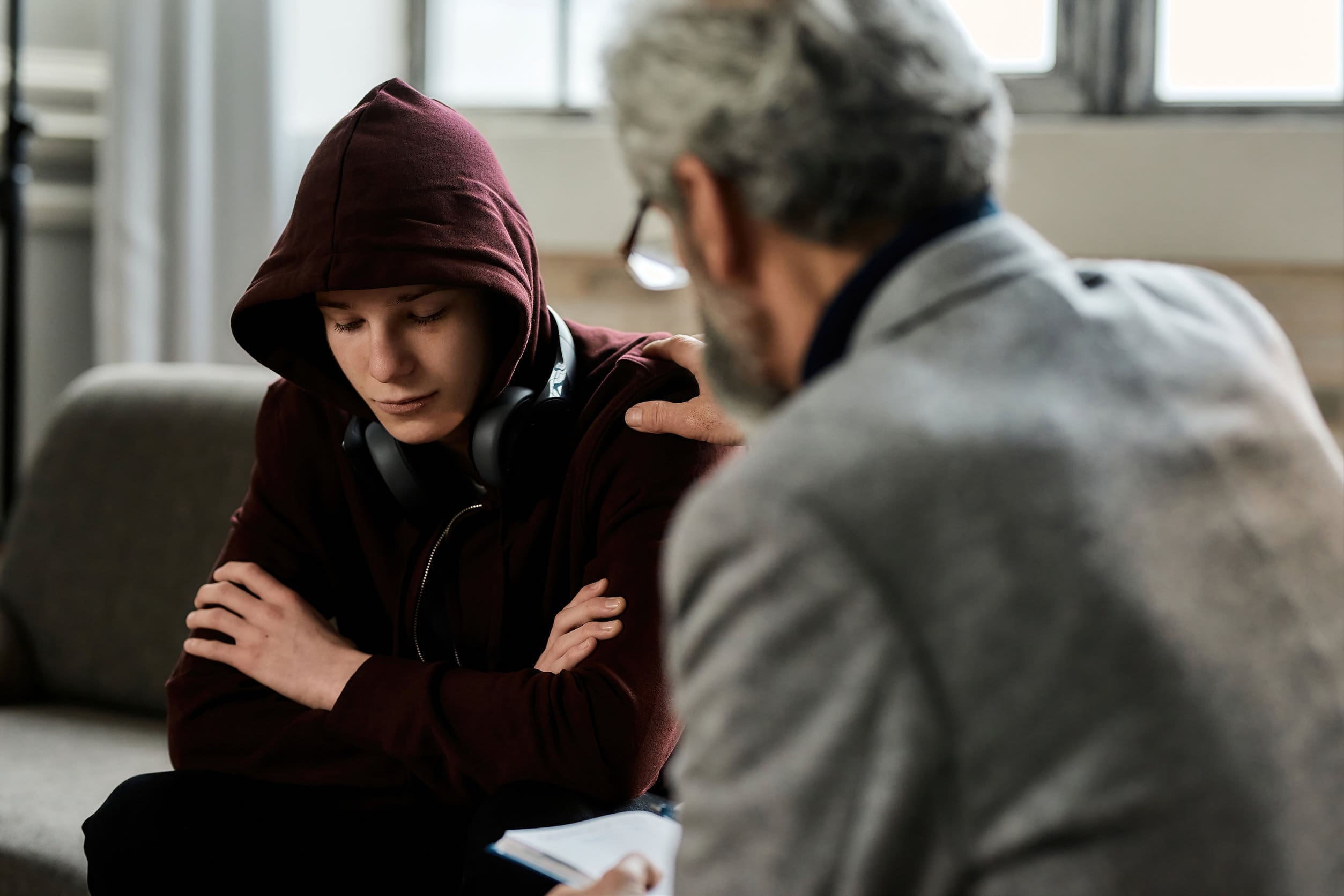 Therapist using CBT to support depressed teenage boy during appointment